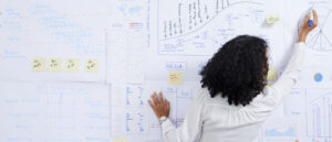 Businesswoman with curly hair drawing diagram on whiteboard when preparing for data-driven marketing presentation