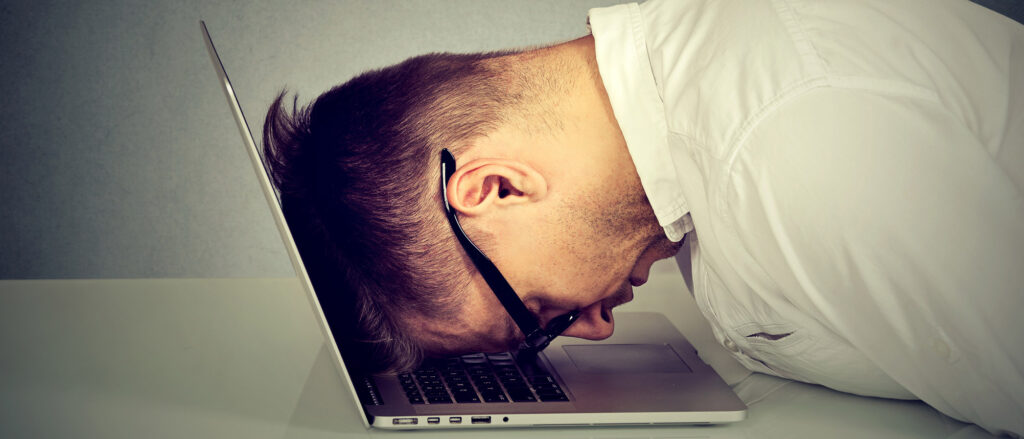 Desperate employee stressed man resting head on laptop