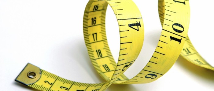Close up of curled yellow measuring tape on white background.
