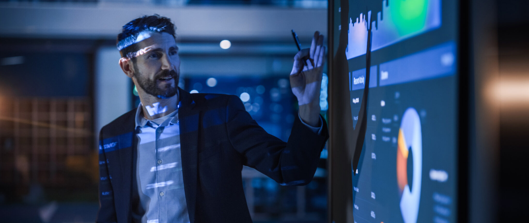 business man pointing at charts and data on a digital board