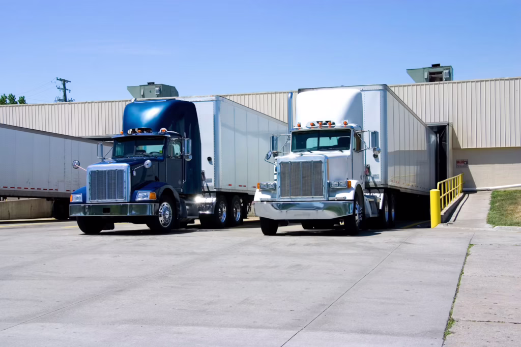 2 semi trucks parked at a warehouse